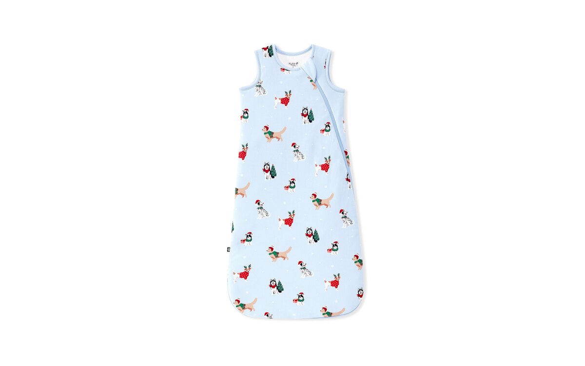The Kyte Baby 1.0 TOG sleep bag in the Holiday Pups print, a pale blue bamboo sleep bag covered in dogs in Santa hats, photographed flat on white.