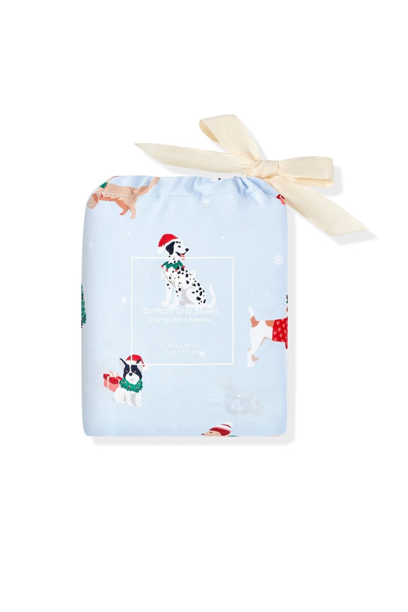 The Kyte Baby crib sheet in the Holiday Pups print, folded and tied with a cream ribbon, photographed on white.