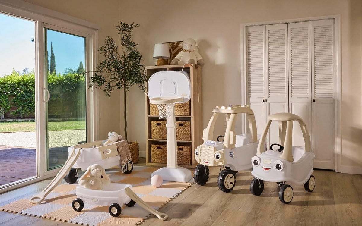 Six Cloud Collection pieces in white and cream arranged in a neutral playroom: two wagons, the basketball set, the Cozy Truck and the Cozy Coupe.
