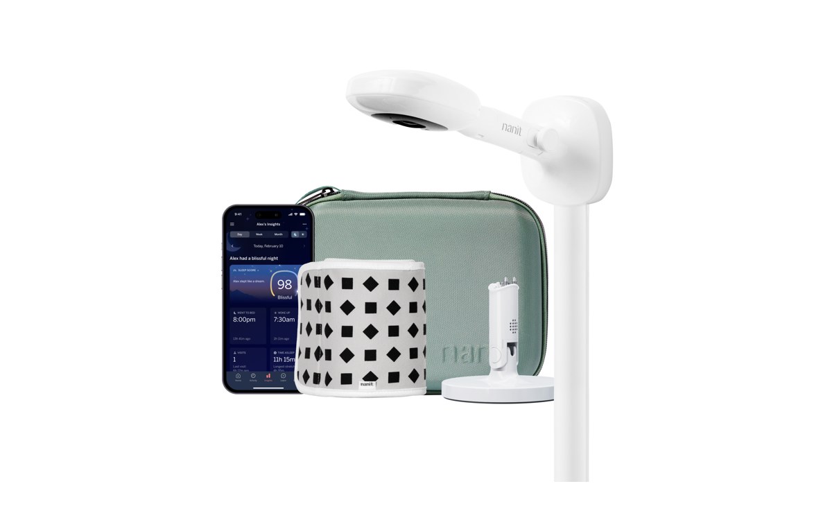 The Nanit Pro baby monitor on its wall mount, white, with the Nanit app on a phone, on a white background.