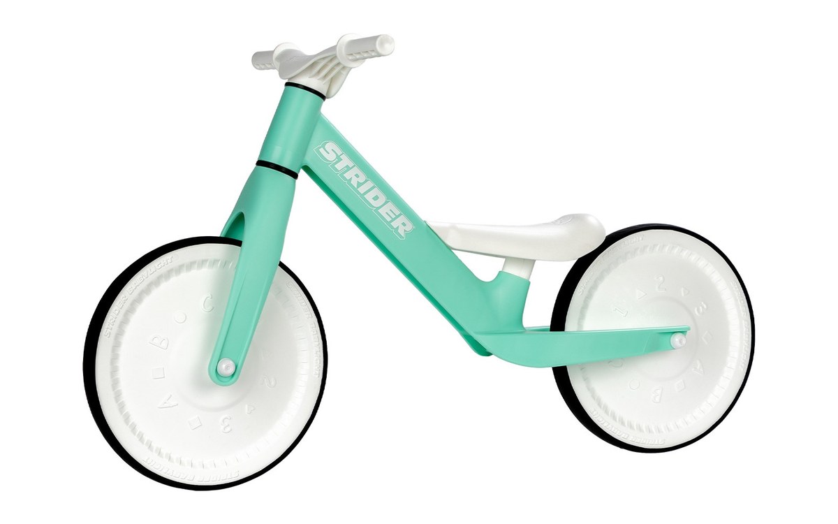 The Strider Baby Balance Bike in green, side on, with white closed wheels and a white seat.