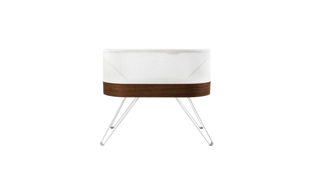The SNOO Smart Sleeper bassinet, white mesh with a walnut band and white legs, photographed on a white background.